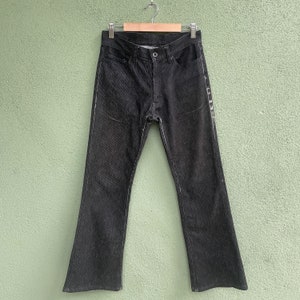 Op de afbeelding: Donkergrijze denim jeans met witte stiksels. De jeans hangen aan een houten kleerhanger tegen een lichtgroene achtergrond. De jeans hebben een klassiek ontwerp met vijf zakken en een rechte pijp.