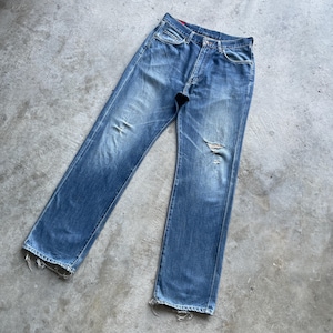 Pu&ograve; includere: Jeans in denim blu sbiadito con un aspetto invecchiato. I jeans hanno un classico design a cinque tasche, una chiusura con bottoni e un aspetto usurato con alcuni strappi. L'orlo &egrave; sfilacciato, aggiungendo all'estetica vintage.