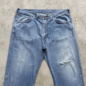 K&ouml;nnte beinhalten: Hellblaue Jeans mit einem aufgerissenen Knie. Die Jeans haben ein klassisches F&uuml;nf-Taschen-Design, einen Knopf- und Rei&szlig;verschluss sowie G&uuml;rtelschlaufen. Der Denim hat ein verwaschenes Aussehen.