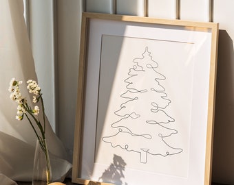 May include: A framed print of a minimalist line drawing of a pine tree in a light wood frame. The frame is sitting on a wooden floor with a gold tray and decorative objects.