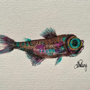 May include: Watercolor painting of a colorful fish. The fish has a brown body with purple and teal accents. The eye is large and teal with a yellow ring. The tail and fins are purple and teal. Signed "Lindsey".