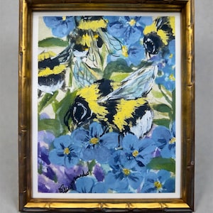 May include: A framed painting of bumblebees amidst blue and purple flowers. The bees are depicted with yellow and black stripes, with some wings visible. The artwork is set in a gold-colored bamboo-style frame.