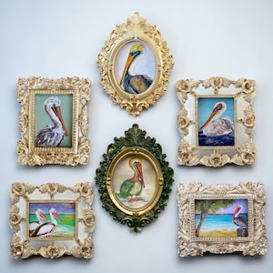 May include: A collection of six framed pelican paintings. The frames are ornate, with gold and ivory finishes. The paintings depict pelicans in various settings, with blue, green, and yellow hues.