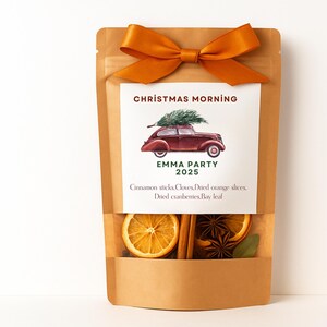 May include: A brown paper bag tied with an orange bow, containing dried orange slices, cinnamon sticks, and star anise. The bag has a label that reads "Christmas Morning" and "EMMA PARTY 2025".