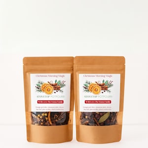 May include: Two brown kraft paper pouches containing stovetop potpourri. The labels feature the text Christmas Morning Magic, STOVETOP POTPOURRI, and With Love, The Emma Family, with illustrations of orange slices, cinnamon, and pine.