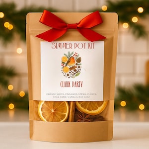May include: A brown paper pouch with a red satin bow containing a simmer pot kit. The label features a robin, orange slices, and pinecones with the text Simmer Pot Kit, Clark Party, and a list of ingredients: orange slices, cinnamon sticks, cloves, star anise, vanilla, bay leaf.