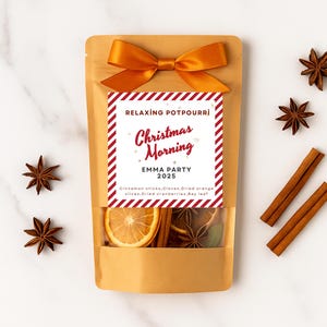 May include: A brown paper bag tied with an orange bow, containing potpourri. The label reads "Relaxing Potpourri Christmas Morning EMMA PARTY 2025." Cinnamon sticks, star anise, and dried orange slices are visible.