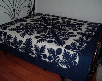 May include: A navy blue and white Hawaiian quilt with a floral pattern. The quilt is made of cotton and is hand-stitched. It is a traditional Hawaiian quilt and is a beautiful example of Hawaiian craftsmanship.