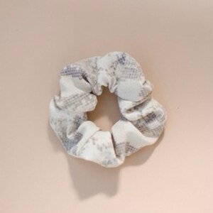 May include: A white and gray patterned scrunchie hair tie.