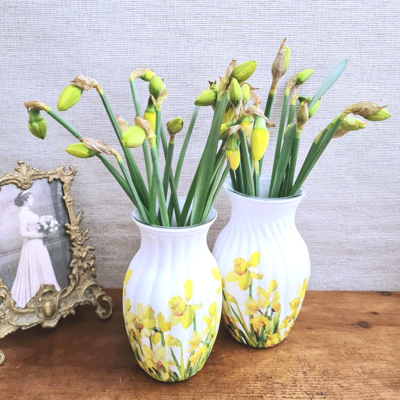 Spring Daffodils glass vase, A beautiful glass vase which has been decoupaged with vibrant yellow spring daffodils all around the vase creating a cheerful and uplifting display. set against a hand painted white chalk paint background giving it a rustic feel with natural twine tied around the vase. Height 20 cm width 11 cm