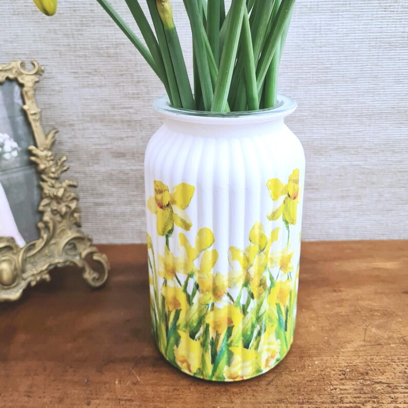 Spring Daffodils glass vase, A beautiful glass vase which has been decoupaged with vibrant yellow spring daffodils all around the vase creating a cheerful and uplifting display. set against a hand painted white chalk paint background giving it a rustic feel with natural twine tied around the vase. Height 20 cm width 11 cm