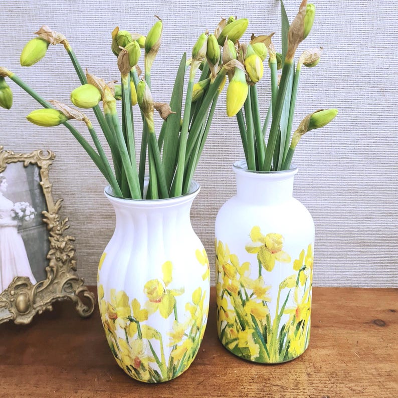 Spring Daffodils glass vase, A beautiful glass vase which has been decoupaged with vibrant yellow spring daffodils all around the vase creating a cheerful and uplifting display. set against a hand painted white chalk paint background giving it a rustic feel with natural twine tied around the vase. Height 20 cm width 11 cm