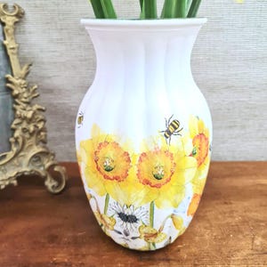 Spring daffodils tulip shaped glass vase, A pretty glass vase decoupaged with vibrant yellow daffodils with butterflies and bees amongst the flowers adding a touch of charm. against a hand painted in white chalk paint background giving a lovely rustic country feel with natural twine tied around the neck of the vase height 20 cm width 14 cm sealed to protect