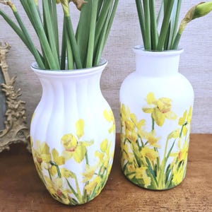 Spring Daffodils glass vase, A beautiful glass vase which has been decoupaged with vibrant yellow spring daffodils all around the vase creating a cheerful and uplifting display. set against a hand painted white chalk paint background giving it a rustic feel with natural twine tied around the vase. Height 20 cm width 11 cm
