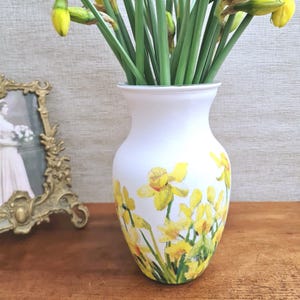 Spring Daffodils glass vase, A beautiful glass vase which has been decoupaged with vibrant yellow spring daffodils all around the vase creating a cheerful and uplifting display. set against a hand painted white chalk paint background giving it a rustic feel with natural twine tied around the vase. Height 20 cm width 11 cm