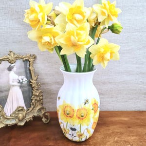Spring daffodils tulip shaped glass vase, A pretty glass vase decoupaged with vibrant yellow daffodils with butterflies and bees amongst the flowers adding a touch of charm. against a hand painted in white chalk paint background giving a lovely rustic country feel with natural twine tied around the neck of the vase height 20 cm width 14 cm sealed to protect