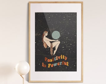 May include: A framed print with a black background and a woman holding a blue orb. The text "Positivity is Powerful" is written in colorful letters.