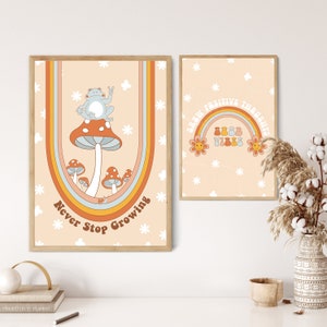 May include: Two framed prints with a retro 70s aesthetic. The print on the left features a blue frog sitting on a mushroom with the text "Never Stop Growing". The print on the right features a rainbow with the text "Good Vibes" and "Good Positive Thoughts".