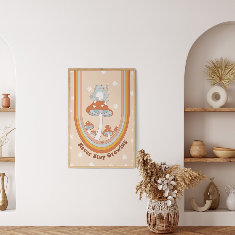 May include: A retro-style poster featuring a blue frog perched on a red and orange mushroom. The mushroom is surrounded by smaller mushrooms and the poster has a rainbow arch with the text "Never Stop Growing" in a groovy font.