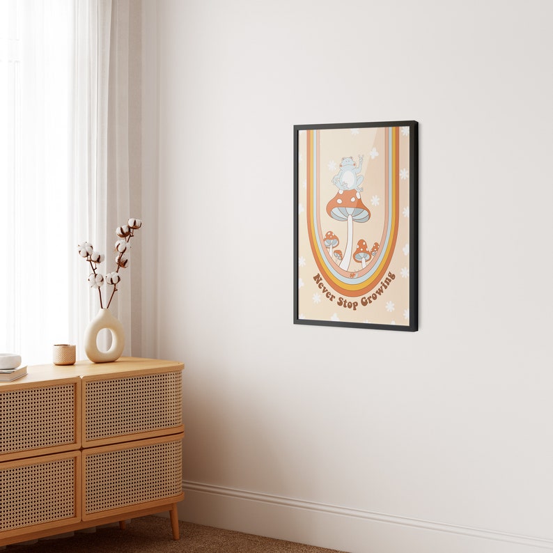 May include: A framed print with a retro design featuring a blue frog sitting on a mushroom with the text "Never Stop Growing" in a rainbow arch.