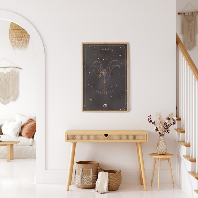 May include: A framed print with a black background and gold accents. The print features a geometric design of a bird with a crescent moon below it. The title "The Fall" is at the top of the print.