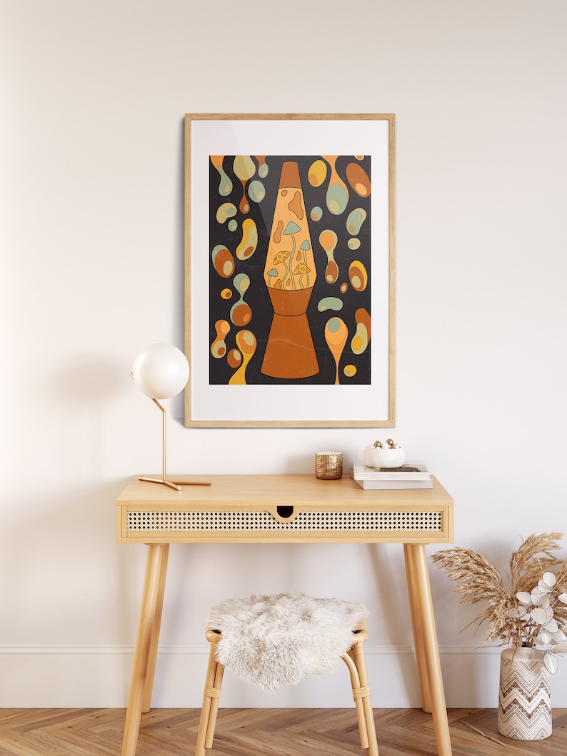 K&ouml;nnte beinhalten: Ein gerahmter Druck einer Retro-Lava-Lampe mit psychedelischem Design. Die Lampe ist mit bunter Fl&uuml;ssigkeit gef&uuml;llt und hat einen pilzf&ouml;rmigen Sockel. Der Druck ist vor einer wei&szlig;en Wand und einem Holztisch mit Schublade platziert.
