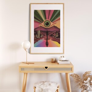 May include: A framed print depicting a surreal desert landscape with a large eye in the sky, a rainbow path, and a lone figure walking towards it.