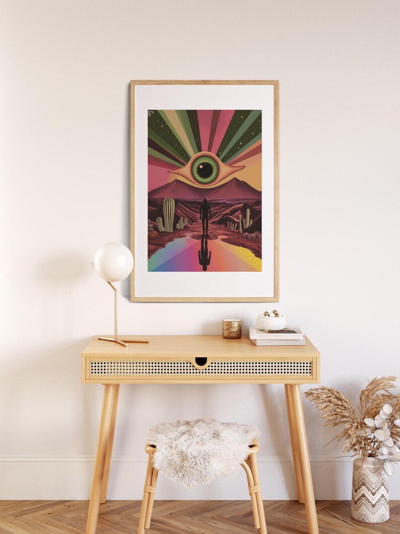 May include: A framed print depicting a surreal desert landscape with a large eye in the sky, a rainbow path, and a lone figure walking towards it.