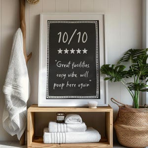 May include: A white framed picture with a black chalkboard inside. The chalkboard has a white handwritten rating of "10/10" with five stars and the text "Great facilities, cosy vibe, will poop here again".