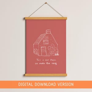 May include: A framed wall art print with a red background and a white line drawing of a house. The text "This is our place, we make the rules" is below the house. The print is held by wooden bars and a string.
