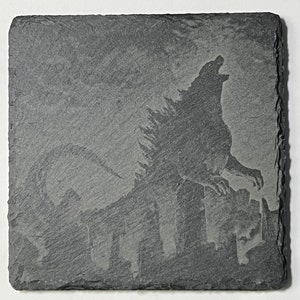 May include: A black slate coaster with a gray silhouette of Godzilla destroying a city.