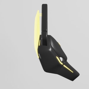 May include: A black and yellow futuristic mask with a geometric design. The mask has a curved shape and a pointed nose.