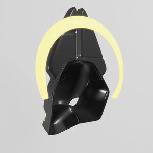 May include: A black, geometric, 3D printed object with a yellow halo around it. The object is shaped like a helmet or a mask.