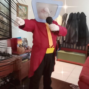 May include: A person in a TV-head costume, wearing a red tailcoat, black trousers, and yellow shoes. The costume includes a light blue TV screen head with antennas and a microphone. The text "Buyer Build! :D" is visible.
