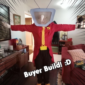 May include: A person in a TV costume with a red coat, yellow tie, and black trousers. The TV head is light blue with a white nose and antenna. The text "Buyer Build! :D" is visible.