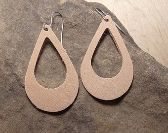 Peut inclure: Une paire de boucles d'oreilles en cuir tanné en forme de larme avec un motif découpé. Les boucles d'oreilles sont suspendues à des crochets argentés.