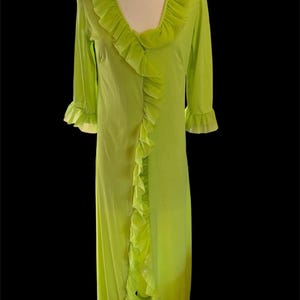 May include: A lime green floor-length robe featuring a deep V-neckline, three-quarter length sleeves with ruffled cuffs, and a cascading ruffle trim that runs along the neckline and down the center front opening of the garment.