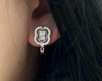 May include: Silver clip-on earrings with a square-shaped diamond in the center surrounded by smaller diamonds.
