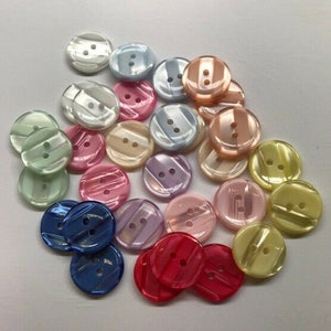 May include: Assortment of colorful two-hole buttons with a pearlescent finish. The buttons are in various shades of pink, blue, green, and yellow.