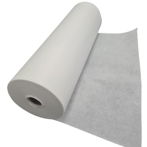 Puede incluir: Un rollo de tejido de entretela no tejido blanco. El tejido está enrollado y una parte del tejido está desenrollado.