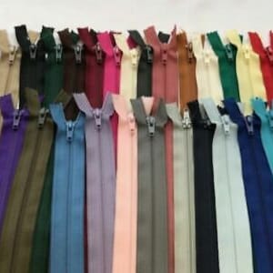May include: Assortment of 24 zipper closures in various colours, including black, white, brown, green, blue, red, and purple. The zippers are all the same size and have a metal slider.