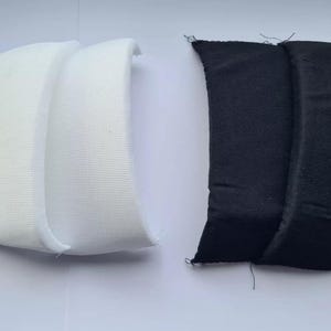 May include: Two pairs of fabric shoe inserts, one white and one black. The inserts are made of a soft, flexible material and are designed to provide extra cushioning and support for the feet.