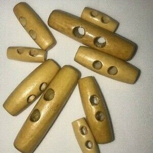 May include: A collection of ten wooden toggle buttons in various sizes. The buttons are all a light brown color and have two holes each.