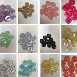 May include: Assortment of 10 different colors of two-hole plastic buttons. The buttons are round and have a shiny finish.