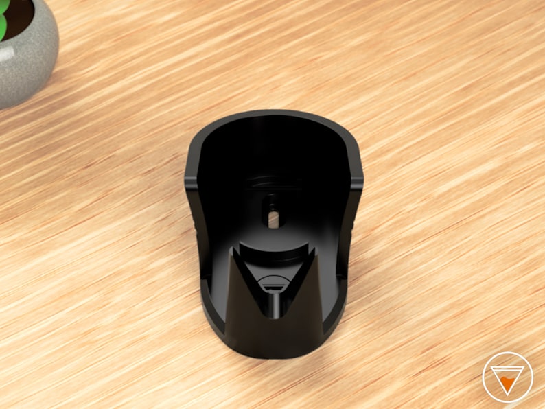 May include: Black plastic wall mount designed to hold a device, such as a phone or speaker, in a vertical position.
