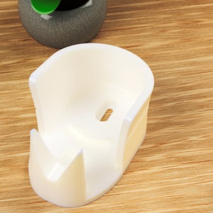 May include: White plastic holder for a roll of tape. The holder has a slot for the tape roll and a small hole for the tape to feed through.