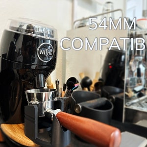 May include: A black Niche Zero coffee grinder with a clear lid and a silver portafilter. The grinder is labeled "Niche" and is compatible with 54mm portafilters. The text "54MM COMPATIBLE" is visible in the image.
