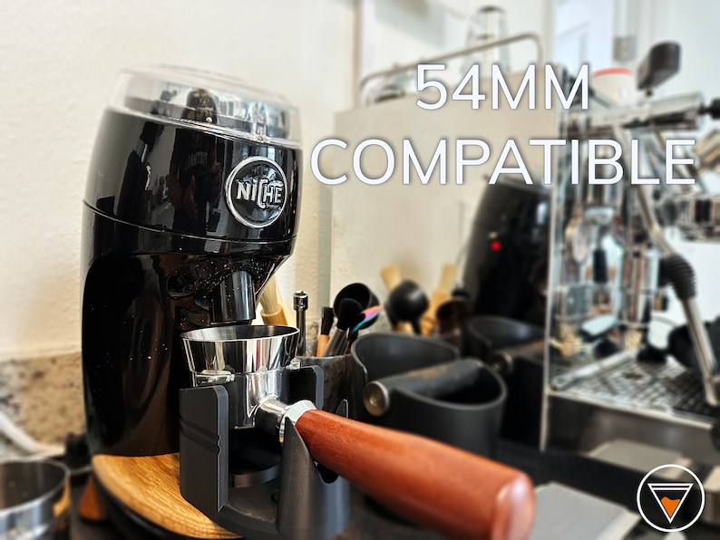 May include: A black Niche Zero coffee grinder with a clear lid and a silver portafilter. The grinder is labeled "Niche" and is compatible with 54mm portafilters. The text "54MM COMPATIBLE" is visible in the image.