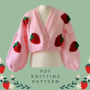 Peut inclure: Un cardigan rose en tricot avec un col en V et des manches longues. Le cardigan est court et présente des applications de fraises brodées sur les manches et le devant. Le texte "PDF KNITTING PATTERN" est imprimé sous le cardigan.