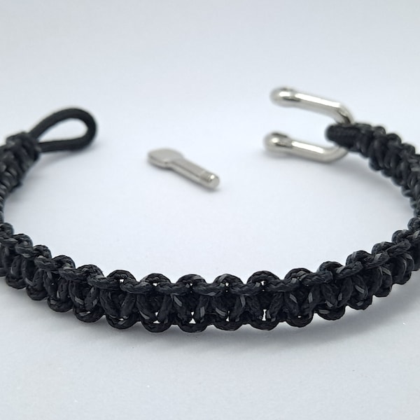 575. Bracelet en paracorde noire et réfléchissante, tressage noeud plat, avec fermoir manille en inox